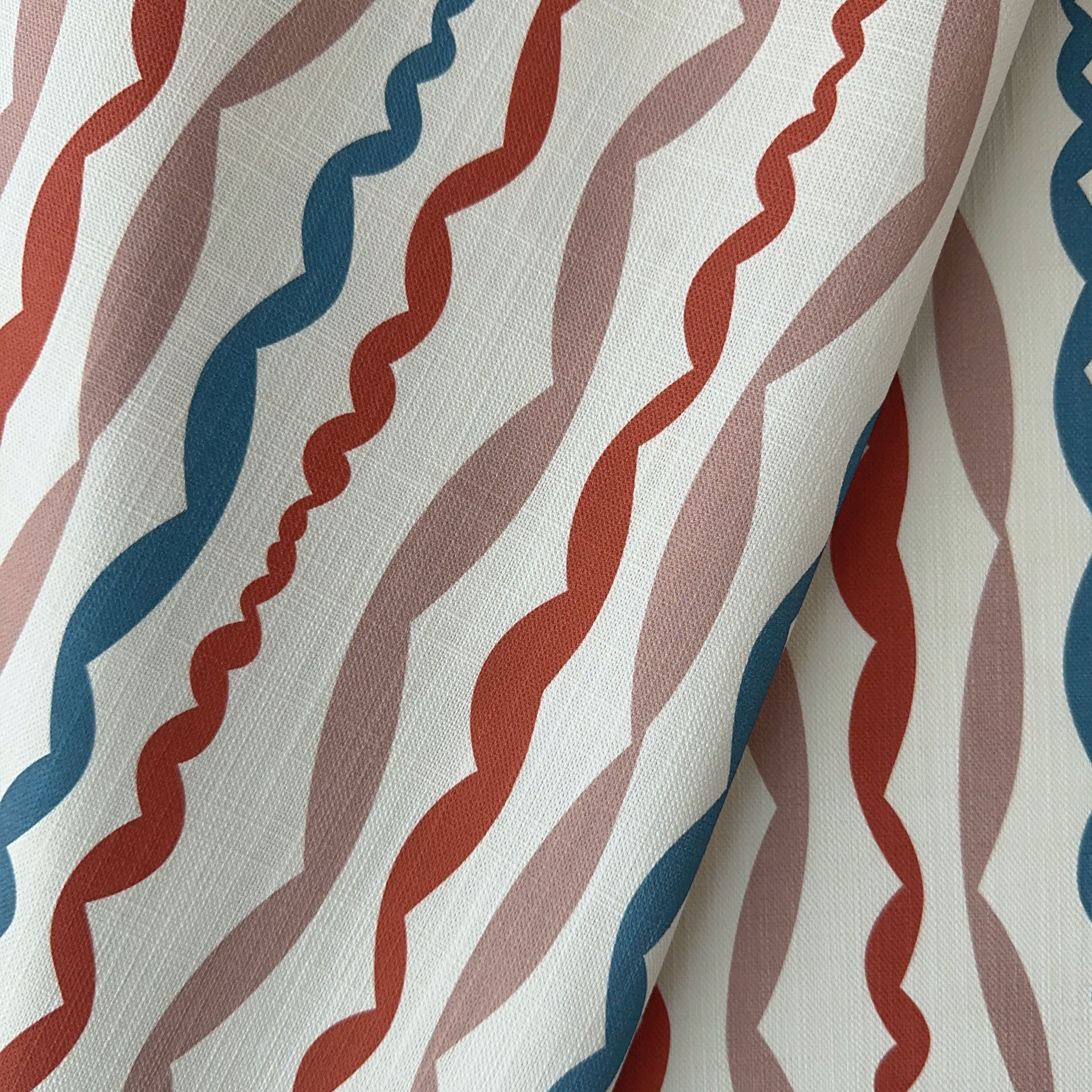 printed fabric with wavy terracotta blue, and beige pattern on a neutral background