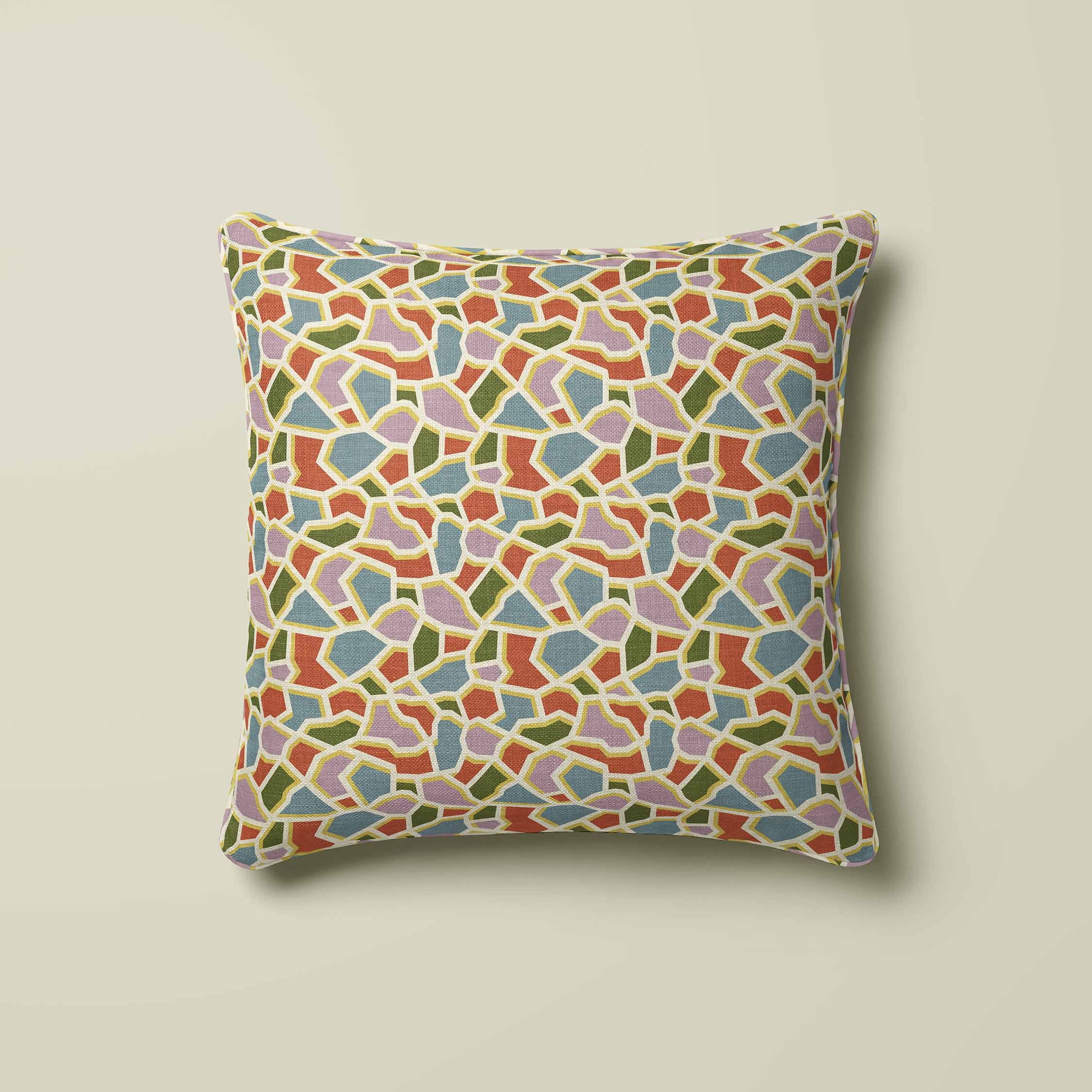 A square throw pillow featuring a colorful mosaic tile pattern in shades of blue, green, orange and pink set outlined in a yellow and light beige background.