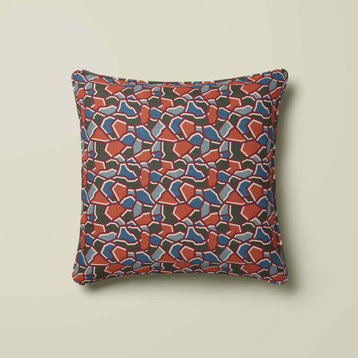 A square throw pillow featuring a colorful abstract mosaic pattern of terracotta, blue, and dark green shapes outlined in cream, set against a solid light beige background.